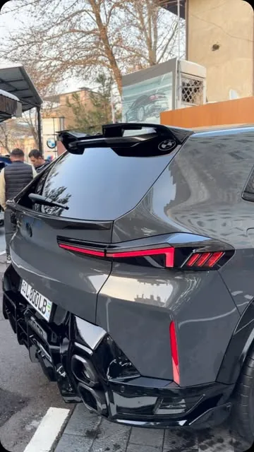BMW XM с карбоновым спойлером у бокса